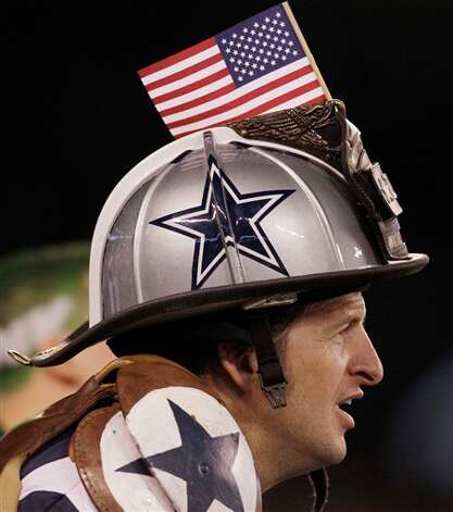 A fan wears a Dallas Cowboys fireman's hat during the first half of an NFL