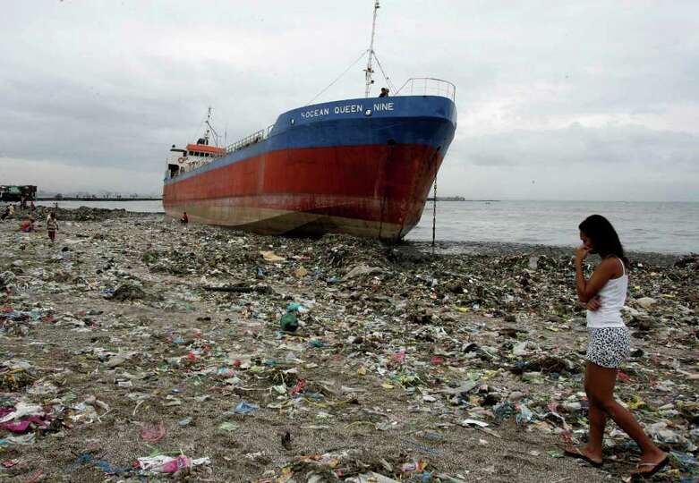 A woman walks by an oil tanker which was washed ashore by Typhoon Nesat in Manila, Philippines, Wedn