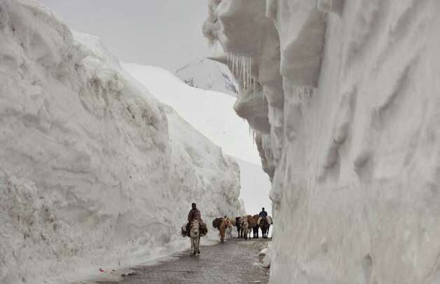 Kashmiri porters on horseback travel past walls of snow along the newly reopened Srinagar-Leh highway in Zojila, about 67 miles east of Srinagar, on Wednesday. The 275-mile-long highway was opened for the season by Indian Army authorities after remaining snow at Zojila Pass, some 11,581 feet above sea level, had been cleared. The pass connects Kashmir with the Buddhist-dominated Ladakh region, a famous tourist destination among foreign tourists for its monasteries, landscapes and mountains. AFP PHOTO/Tauseef MUSTAFA Photo: TAUSEEF MUSTAFA, AFP/Getty Images / 2012 AFP