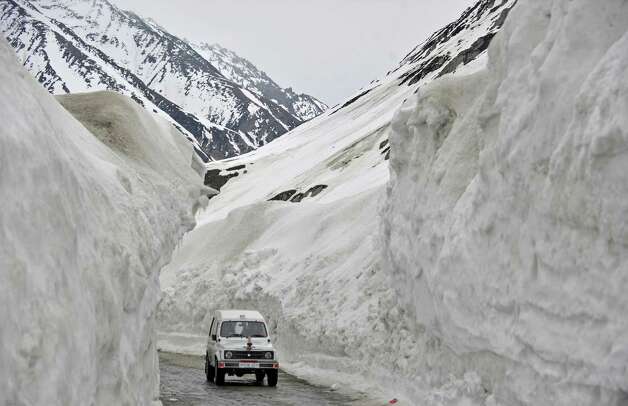 A vehicle plies the Srinagar-Leh highway in Zojila, about 67 miles east of Srinagar, on Wednesday. The 275-mile highway was opened for the season by Indian Army authorities after remaining snow at Zojila Pass, some 11,581 feet above sea level, had been cleared. The pass connects Kashmir with the Buddhist-dominated Ladakh region, a famous tourist destination among foreign tourists for its monasteries, landscapes and mountains. AFP PHOTO/Tauseef MUSTAFA Photo: TAUSEEF MUSTAFA, AFP/Getty Images / 2012 AFP