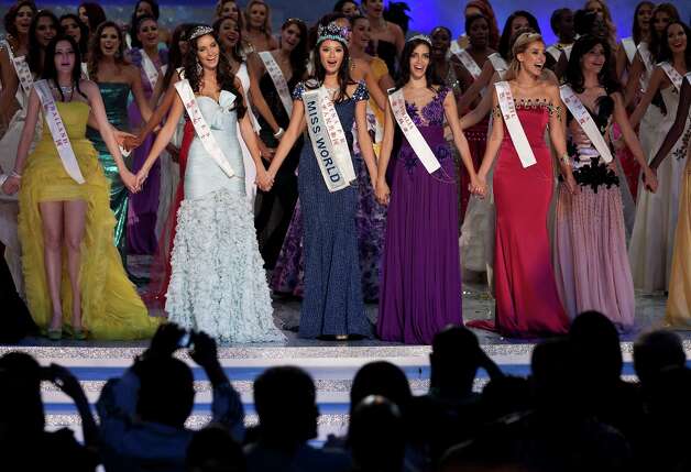 Newly crowned Miss World Yu Wenxia of China, center, holds hands with first runner-up Miss Wales Sophie Moulds, center left, and second runner-up Miss Australia Jessica Kahawaty, center right, as they sing. Photo: AP / SL