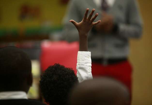 An eager kindergarten student raises his hand to ask teacher Xavier Buster a question. Most of the teachers are black men. Photo: Mike Kepka, The Chronicle / SF