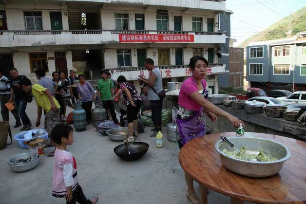 Residents gather to cook a meal in Yiliang, southwest China's Yunnan province on Friday, following two shallow quakes that struck the remote and mountainous border area of Yunnan and Guizhou province of southwest China.   Dozen of people were killed and 550 injured when two shallow quakes with a magnitude of both at 5.6 struck a remote and mountainous area of southwest China, toppling buildings and sparking chaos in the streets, officials said.    ( AFP/AFP/GettyImages) Photo: AFP, Ap/getty / 2012 AFP