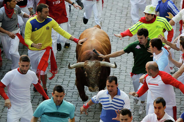 Revelers run with an Alcurrucen's ranch fighting bull entering the bullring during the second day of the San Fermin Running Of The Bulls festival, on July 7, 2013 in Pamplona, Spain. The annual Fiesta de San Fermin, made famous by the 1926 novel of US writer Ernest Hemmingway 'The Sun Also Rises', involves the running of the bulls through the historic heart of Pamplona, this year for nine days from July 6-14. Photo: Pablo Blazquez Dominguez, Getty Images / 2013 Getty Images