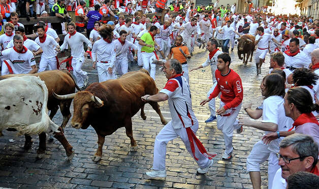 Participants run in front of Alcurrucen's bulls during the first bull run of the San Fermin Festival, on July 7, 2013, in Pamplona, northern Spain. The festival is a symbol of Spanish culture that attracts thousands of tourists to watch the bull runs despite heavy condemnation from animal rights groups. Photo: RAFA RIVAS, AFP/Getty Images / 2013 AFP