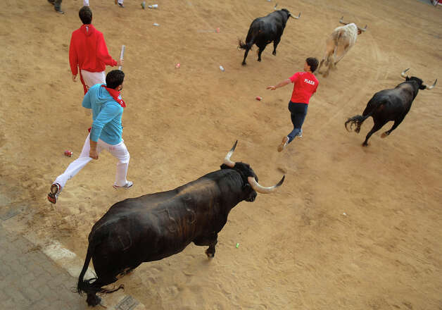 Participants run in front of Dolores Aguirre's bulls during the second bull run of the San Fermin Festival in Pamplona, northern Spain, on July 8, 2013. The festival is a symbol of Spanish culture that attracts thousands of tourists to watch the bull runs despite heavy condemnation from animal rights groups. Photo: PEDRO ARMESTRE, AFP/Getty Images / 2013 AFP