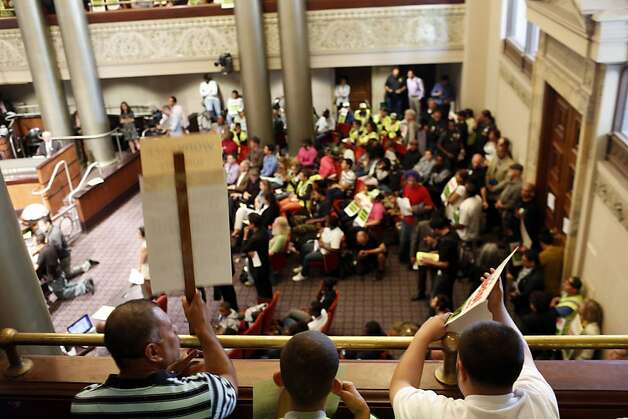 Audience members hold up picket signs during a city council meeting at the Oakland City Hall in Oakland, Calif. on July 30, 2013. Photo: Ian C. Bates, The Chronicle