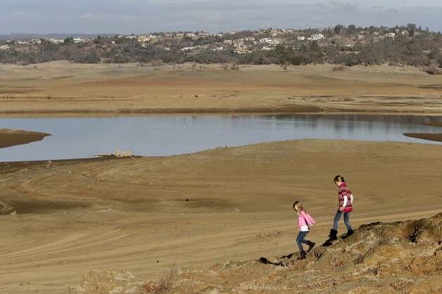 With the edge of Folsom Lake, Calif.,  more than 100 yards away, Gina, 8, left, and Sydney, 9, Gerety walk on rocks that are usually at the waters edge,  Thursday Jan. 9, 2014.  Gov. Jerry Brown officially declared a drought emergency in California, as the state faces a serious water shortage. Reservoirs in the state have dipped to historic lows after one of the driest calendar years on record. Photo: Rich Pedroncelli, Associated Press