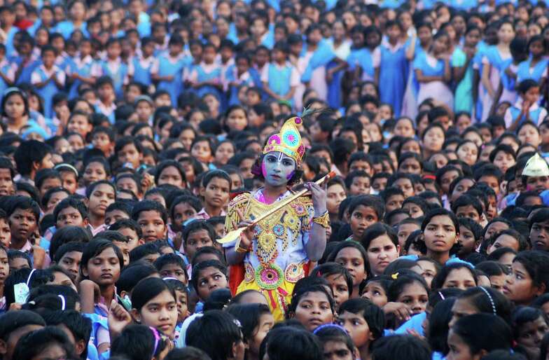 An Indian schoolchild dressed as the Hindu god Krishna and adorned with colored powder stands among other students during celebrations for the spring festival Holi in Bhubaneswar.