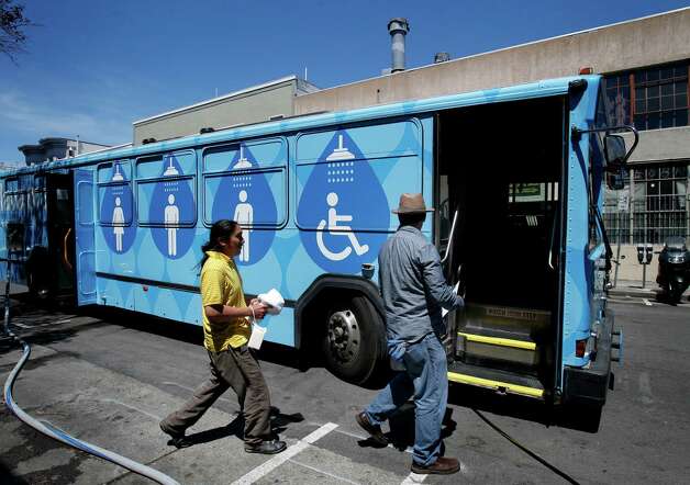 Lava Mae employee Michael McMorrow (right) led Jose Poot to his shower stall in the bus Tuesday June 24, 2014 in San Francisco, Calif. Lava Mae, the program that is turning old MUNI buses into showers for homeless people. began their test run in front of the Mission Neighborhood Resource Center. Photo: Brant Ward, San Francisco Chronicle