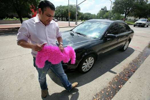 Younus Hyder, a Lyft driver, prepares the company's iconinc pink moustache for the front of his vehicle outside Houston City Hall on Aug. 5. Photo: Mayra Beltran, Staff / © 2014 Houston Chronicle