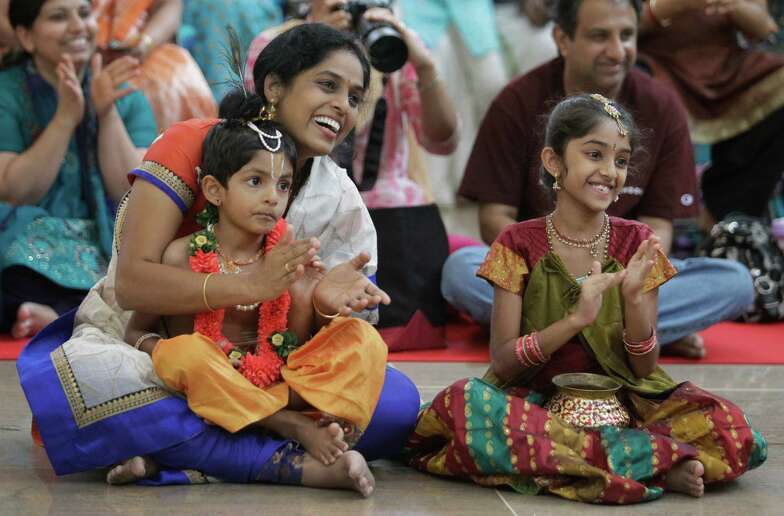 Sujatha Konaragiri with her son, Saketha, 4, and daughter Srividya, 7, applaud for the winners of the children's costume contest during the Krishna Janamashtami activities Saturday in The Woodlands.