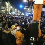 A man dressed in a fuzzy, full-length Giants costume stands above revelers near the intersection of 19th and Mission Street in San Francisco after the Giants win the World Series on Wednesday, October 29, 2014.