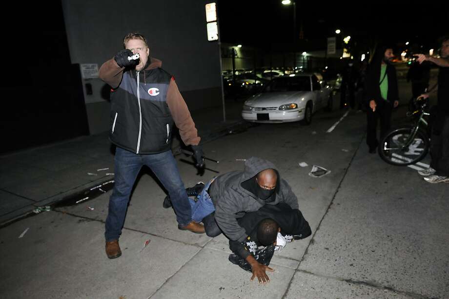An undercover California Highway Patrol officer points a gun at a crowd of protesters and photographers while his partner subdues a demonstrator who struck him in the head in Oakland on Dec. 10. Photo: Michael Short / Special To The Chronicle / ONLINE_YES