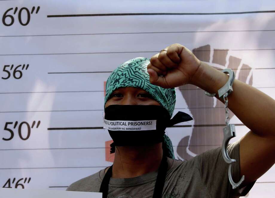 A Filipino activist clenches his fist in front of a mock police mugshot display during a rally by activists and Filipino Muslims in front of the Justice Department in Manila, to protest the continuing detention of their relatives whom they claimed were wrongfully arrested. Photo: Bullit Marquez / Associated Press / AP