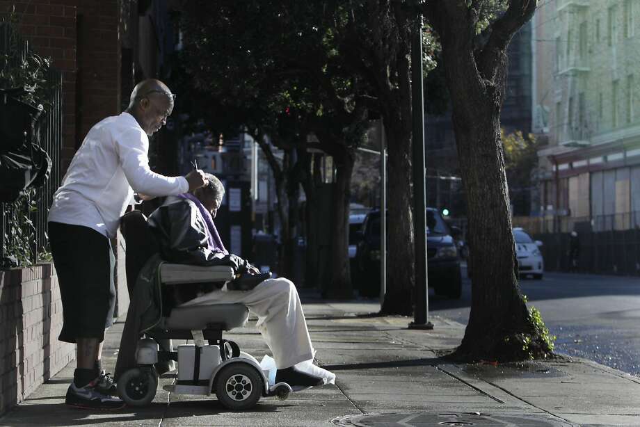 Lloyd Lopez of San Francisco cuts his uncle Mac Blake's hair in the morning sun on the sidewalk across the street from the Renoir Hotel on Thursday, October 29,  2015 in San Francisco, Calif. Photo: Lea Suzuki, The Chronicle