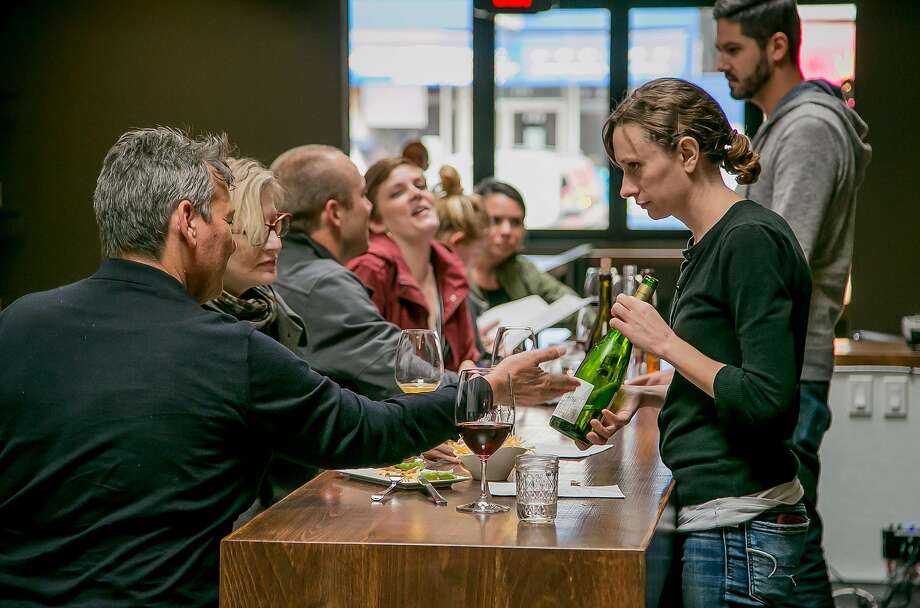 Nichole Ream (right) shows a bottle of wine to a customer at the High Treason wine bar in San Francisco. Photo: John Storey, Special To The Chronicle