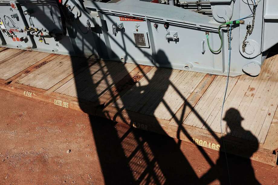 MENTONE, TX - FEBRUARY 05:  The shadows of  workers with Apache Corp. are viewed at the Patterson 298 natural gas fueled drilling rig on land in the Permian Basin on February 5, 2015 in Mentone, Texas.The rig, which is only 21 days old, is the first  drilling rig in Texas that is 100-percent fueled by natural gas. As crude oil prices have fallen nearly 60 percent globally, many American communities that became dependent on oil revenue are preparing for hard times. Texas, which benefited from hydraulic fracturing and the shale drilling revolution, tripled its production of oil in the last five years. The Texan economy saw hundreds of billions of dollars come into the state before the global plunge in prices. Across the state drilling budgets are being slashed and companies are notifying workers of upcoming layoffs. According to federal labor statistics, around 300,000 people work in the Texas oil and gas industry, 50 percent more than four years ago.  (Photo by Spencer Platt/Getty Images) Photo: Spencer Platt, Staff / 2015 Getty Images
