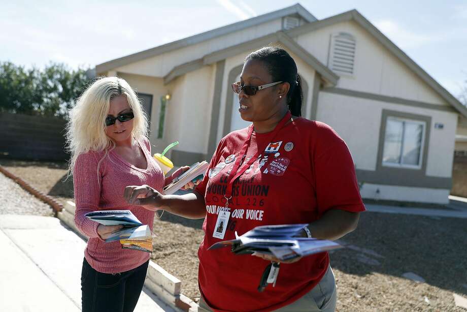 Union member Annette De Campos (right) talks with a voter as De Campos canvasses a neighborhood in Las Vegas.