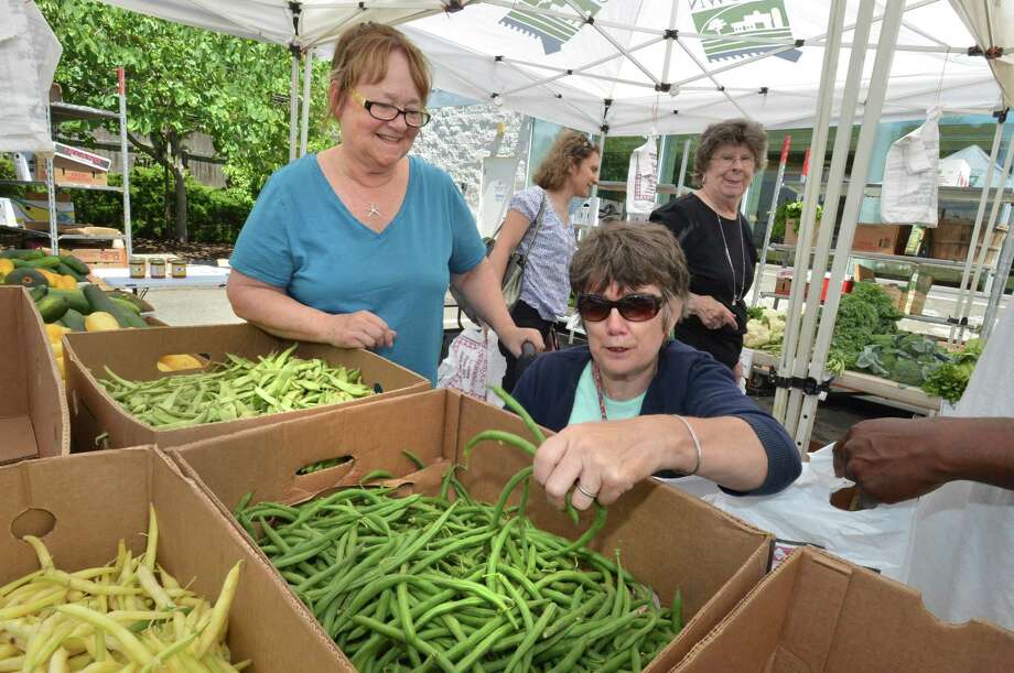 Market master for the city of Norwalk’s farm stands, Lyn Detroy, helps Lisette Cimcke grab some fresh picked string beans from the Country Farms farm stand at Norwalk Community Health Center on Wednesday, July 26, in Norwalk. Cimcke is not able to use the state supplied voucher for seniors, which is being cut due to budget restraints. Photo: Alex Von Kleydorff / Hearst Connecticut Media / Norwalk Hour