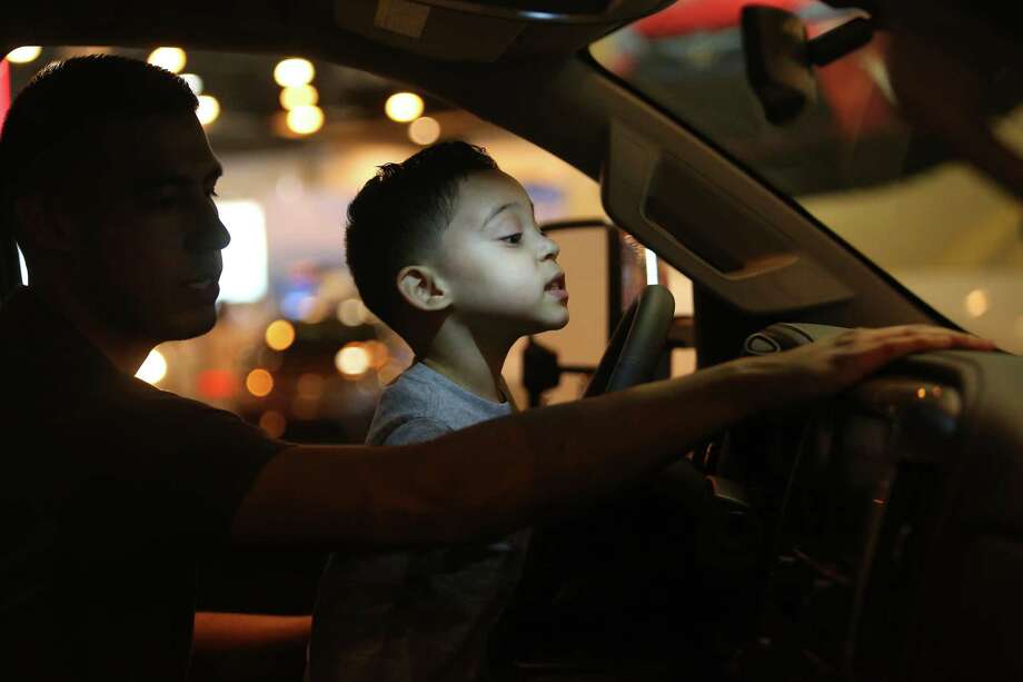 Ian Castaneda, 3, sits on the lap of his father, Aaron, as they check out a truck Thursday at the Houston Auto Show.  Photo: Mark Mulligan, Staff Photographer / 2017 Mark Mulligan / Houston Chronicle