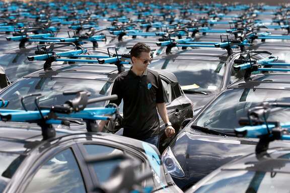 Head of operations Edmund Solis walks among the fleet of a Gig car share vehicles at a AAA storage yard in Oakland, Calif. on Thursday, April 13, 2017. The fleet of 250 Priuses, each with two bike racks mounted to the roof, takes to the streets of Berkeley and Oakland on April 30, when the automobile club's car sharing service launches.