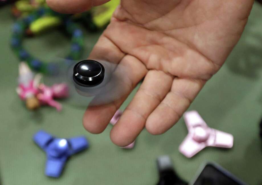 A toys store owner plays with a fidget spinner in Oxford, Mich. A consumer advocacy group says two types of fidget spinners being sold at Target could be dangerous due to lead content. Photo: Carlos Osorio /Associated Press / The Observer